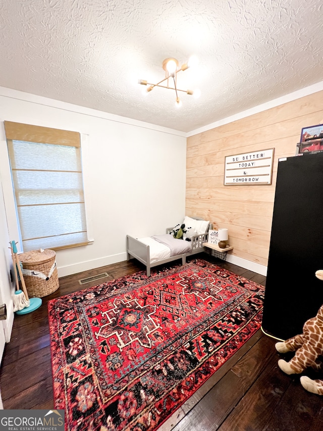 sitting room with a textured ceiling, wood walls, a notable chandelier, and hardwood / wood-style flooring