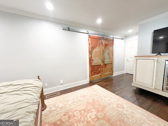 bedroom featuring a barn door, dark hardwood / wood-style floors, and ornamental molding