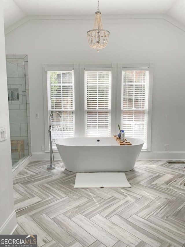 bathroom featuring a healthy amount of sunlight, lofted ceiling, plus walk in shower, and an inviting chandelier