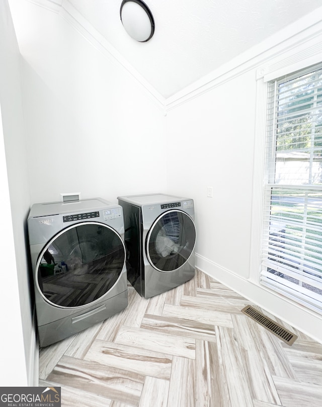 clothes washing area featuring washer and clothes dryer, ornamental molding, and light parquet floors