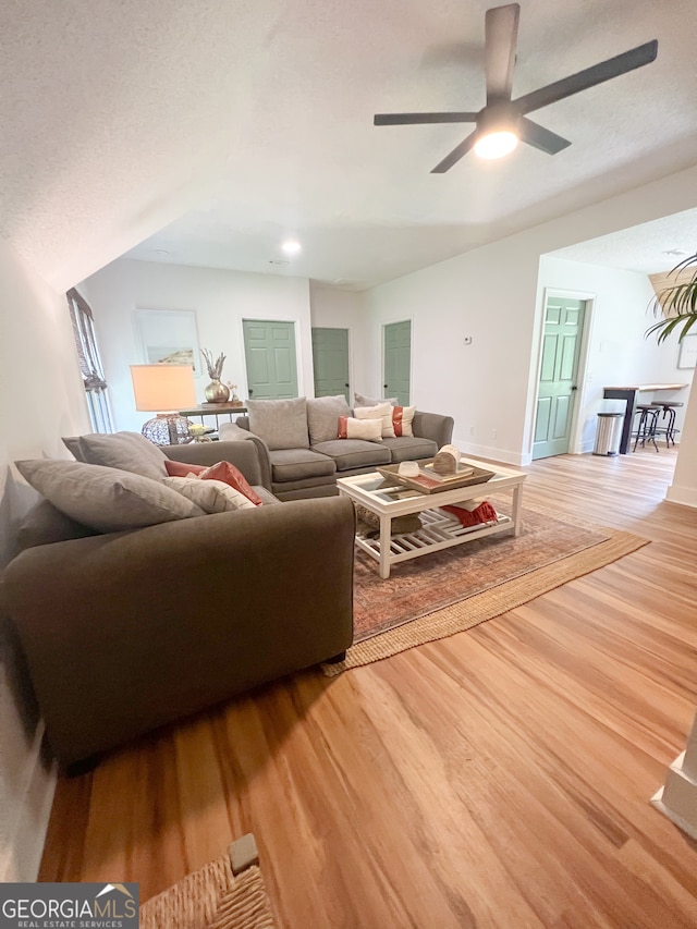 living room featuring ceiling fan, wood-type flooring, and a textured ceiling