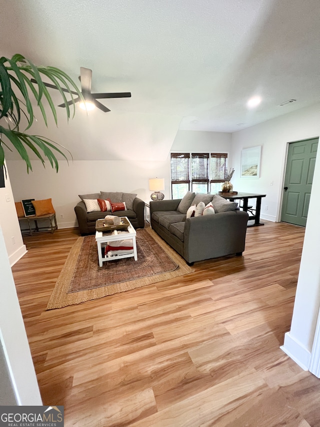 living room featuring a textured ceiling, light hardwood / wood-style floors, and ceiling fan