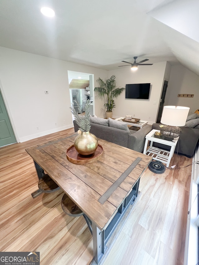 dining room featuring ceiling fan, light hardwood / wood-style floors, and vaulted ceiling