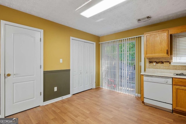 kitchen featuring dishwasher, light hardwood / wood-style floors, tasteful backsplash, and a textured ceiling