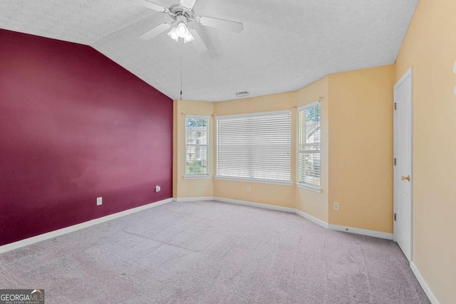 carpeted empty room featuring lofted ceiling, ceiling fan, and a textured ceiling