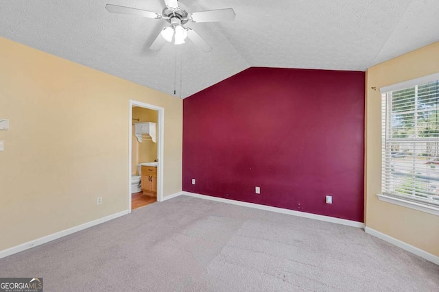 unfurnished room with ceiling fan, light colored carpet, lofted ceiling, and a wealth of natural light