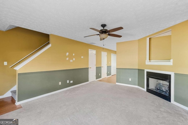 unfurnished living room with light carpet, a textured ceiling, and ceiling fan