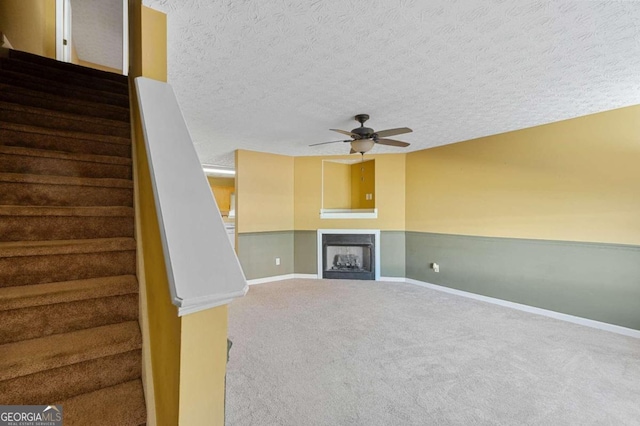 3127 Fields Dr, Stonecrest, GA 30038 - unfurnished living room featuring carpet flooring, a textured ceiling, a ceiling fan, stairs, and a fireplace