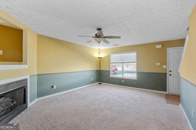 unfurnished living room with carpet floors, a textured ceiling, and ceiling fan