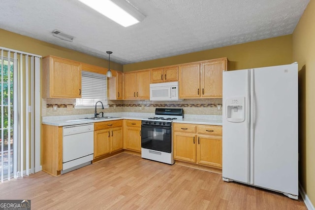 kitchen featuring white appliances, sink, light hardwood / wood-style floors, pendant lighting, and backsplash