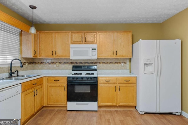 kitchen featuring white appliances, sink, light hardwood / wood-style floors, hanging light fixtures, and a textured ceiling