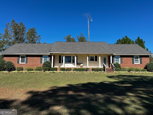 ranch-style home featuring covered porch and a front yard