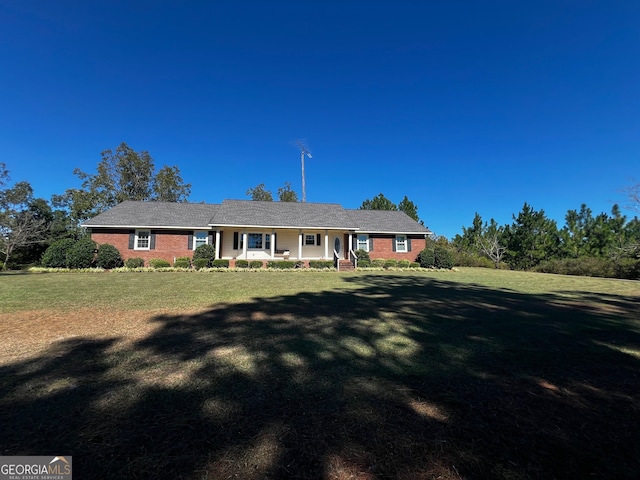 ranch-style house featuring covered porch and a front yard