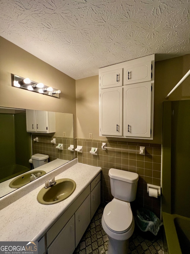 bathroom with a textured ceiling, tile walls, and sink