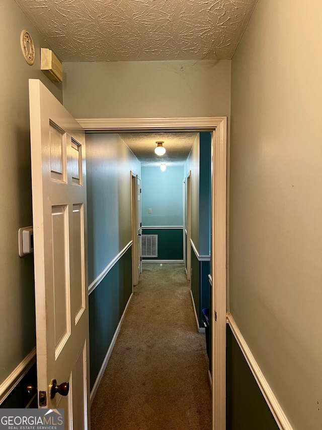 hallway with carpet and a textured ceiling