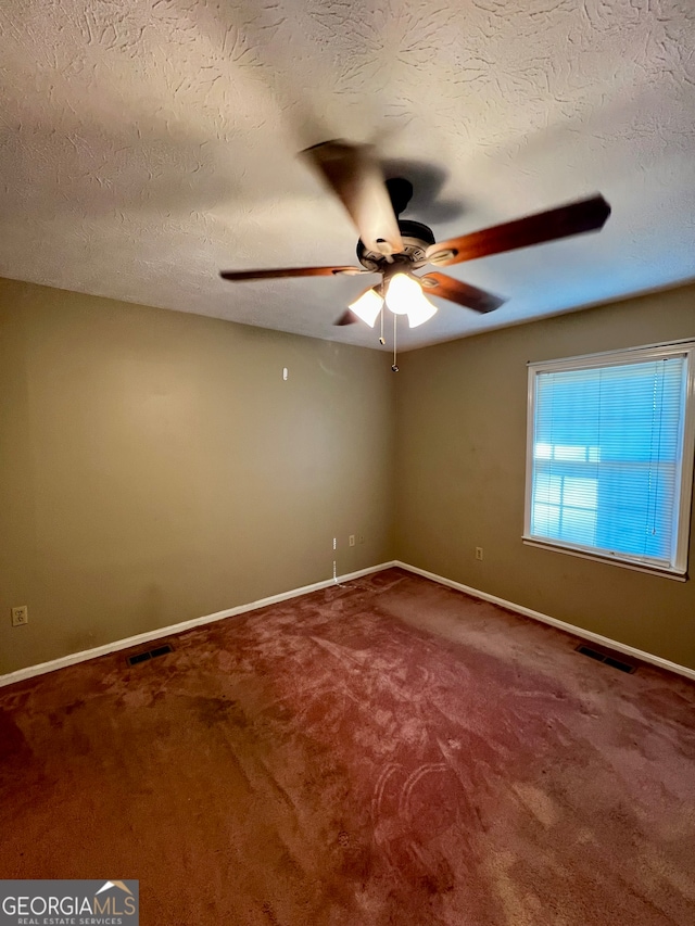 empty room with ceiling fan, carpet, and a textured ceiling