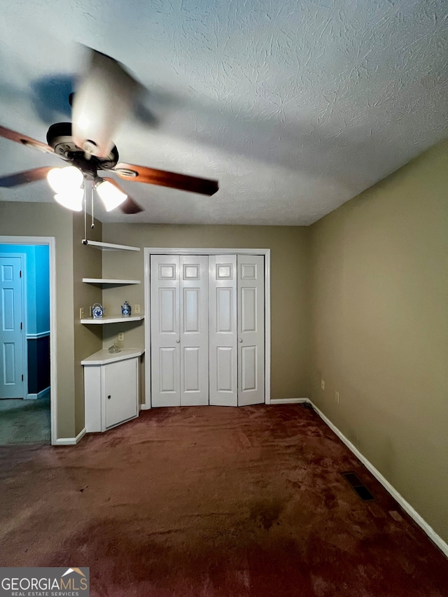 unfurnished bedroom with ceiling fan, carpet floors, and a textured ceiling