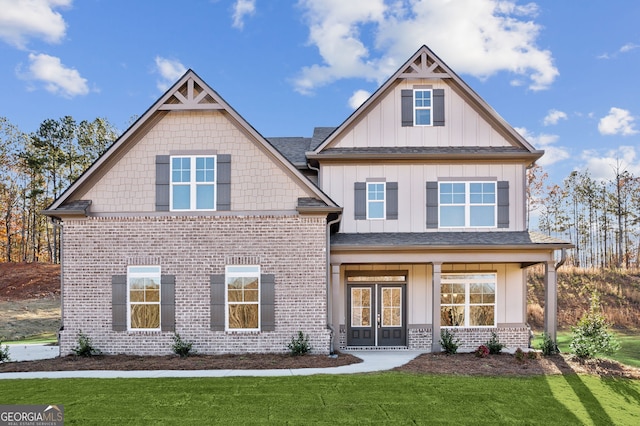 craftsman-style home featuring board and batten siding, french doors, brick siding, and a front lawn