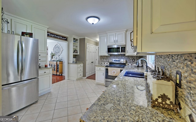 kitchen with sink, white cabinetry, tasteful backsplash, stainless steel appliances, and light stone countertops