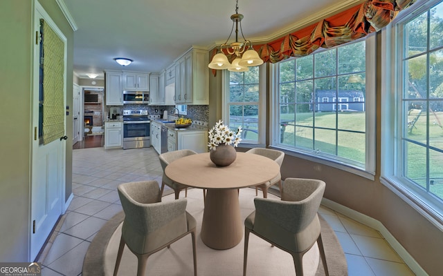 dining space featuring light tile patterned flooring, sink, a notable chandelier, and crown molding