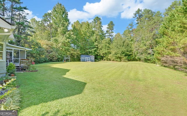 view of yard with a deck, a sunroom, and a storage unit