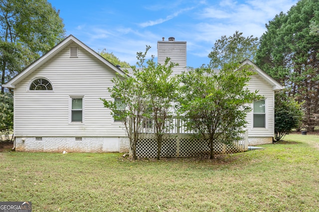 rear view of property featuring a wooden deck and a lawn