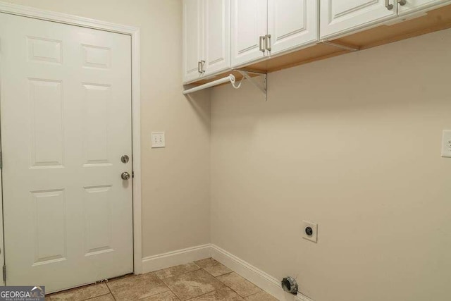 laundry room with hookup for an electric dryer, cabinets, and light tile patterned floors