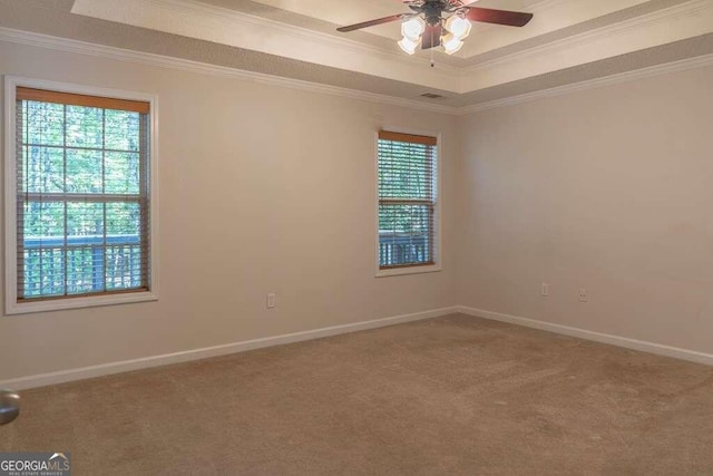 carpeted spare room with ornamental molding, a tray ceiling, and ceiling fan