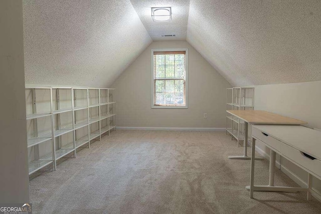 bonus room featuring lofted ceiling, light colored carpet, and a textured ceiling