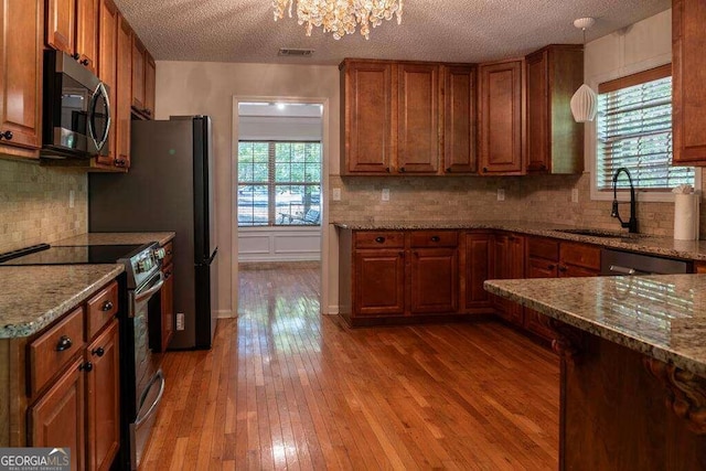 kitchen featuring light wood-type flooring, a healthy amount of sunlight, stainless steel appliances, and a textured ceiling