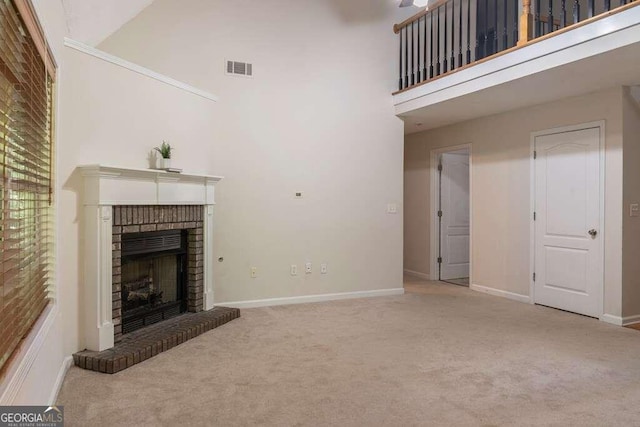 unfurnished living room featuring light carpet, a fireplace, and a towering ceiling