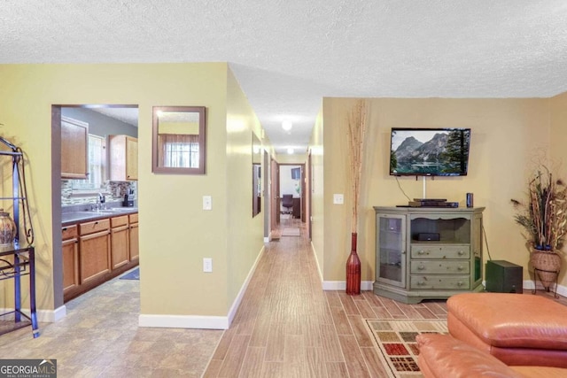 living room featuring light hardwood / wood-style flooring, sink, and a textured ceiling