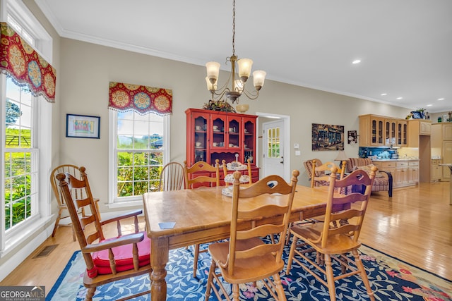 dining area with plenty of natural light, light hardwood / wood-style floors, a chandelier, and ornamental molding