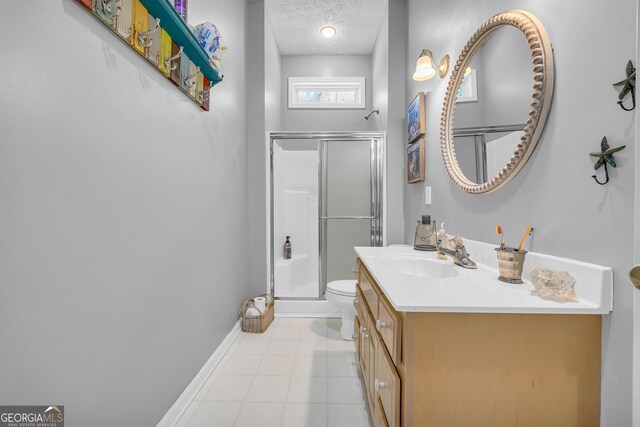 bathroom with vanity, a textured ceiling, tile patterned floors, toilet, and a shower with door