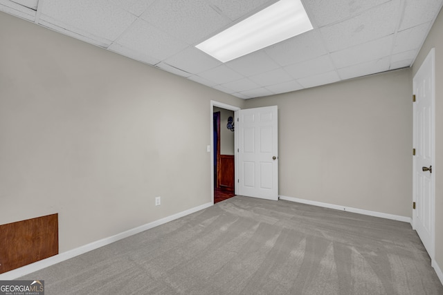 empty room with a drop ceiling and carpet flooring