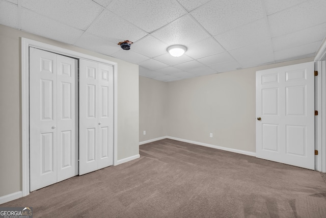 unfurnished bedroom with a closet, a drop ceiling, and carpet flooring