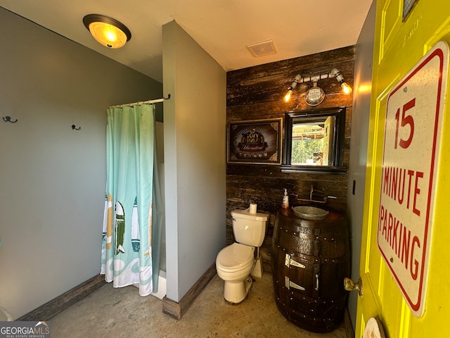 bathroom featuring concrete flooring, a shower with shower curtain, and toilet