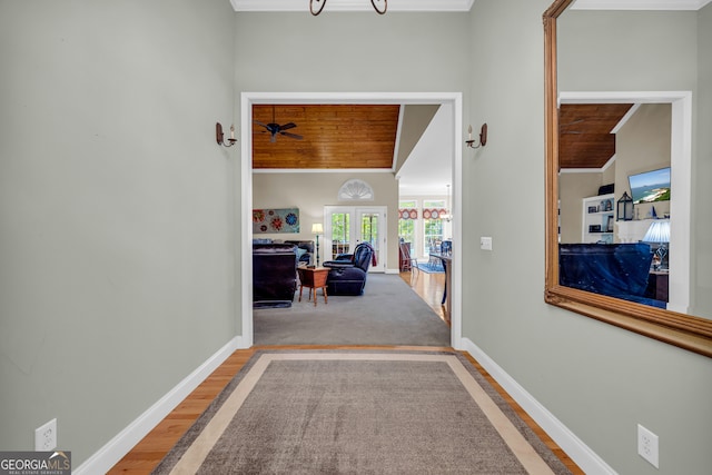 corridor with ornamental molding, hardwood / wood-style floors, and wood ceiling