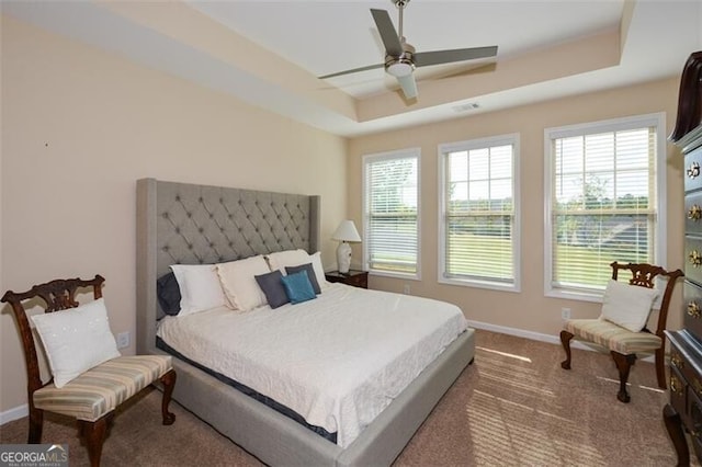 bedroom with ceiling fan, a raised ceiling, and carpet flooring