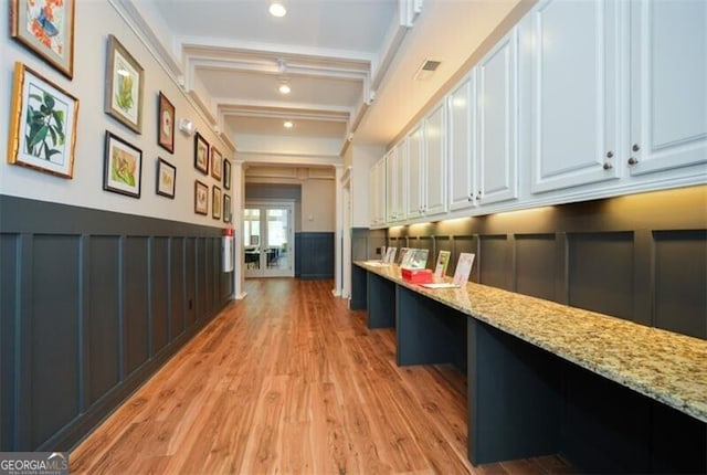 corridor featuring ornamental molding, beam ceiling, and light hardwood / wood-style flooring