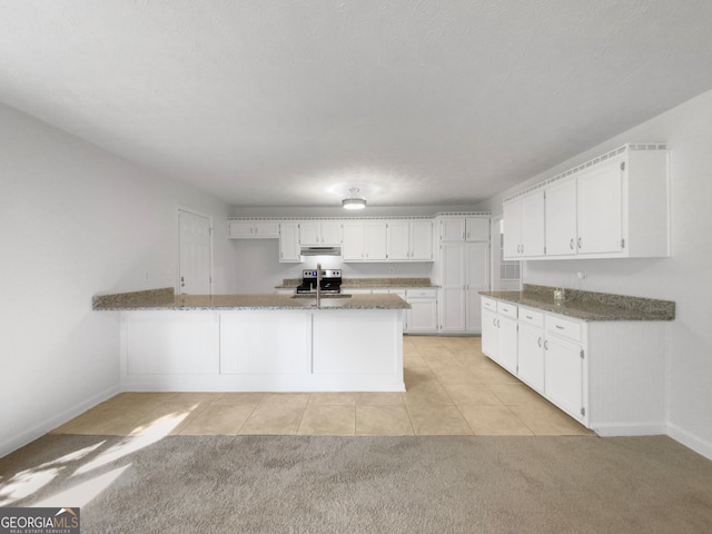 kitchen with light colored carpet, dark stone counters, sink, and white cabinetry