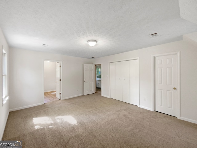 unfurnished bedroom featuring a textured ceiling and light colored carpet