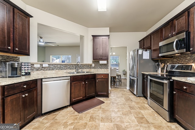 kitchen featuring tasteful backsplash, appliances with stainless steel finishes, sink, dark brown cabinetry, and light stone counters