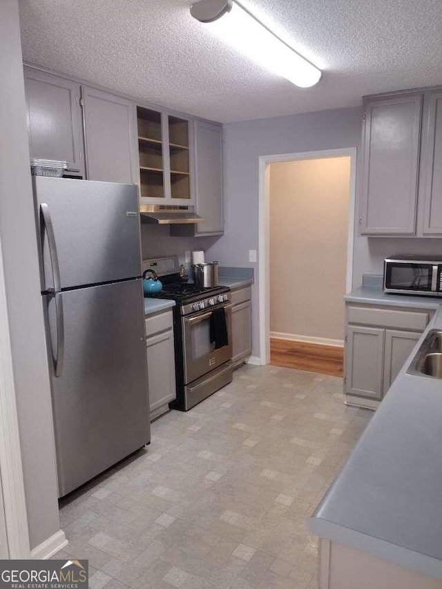 kitchen featuring stainless steel appliances, sink, gray cabinetry, and a textured ceiling