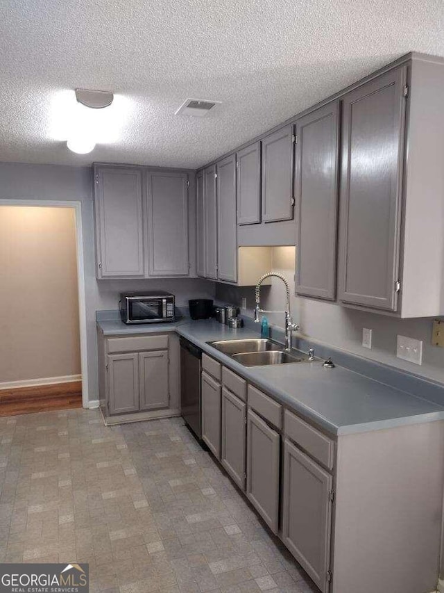 kitchen with appliances with stainless steel finishes, sink, gray cabinetry, and a textured ceiling