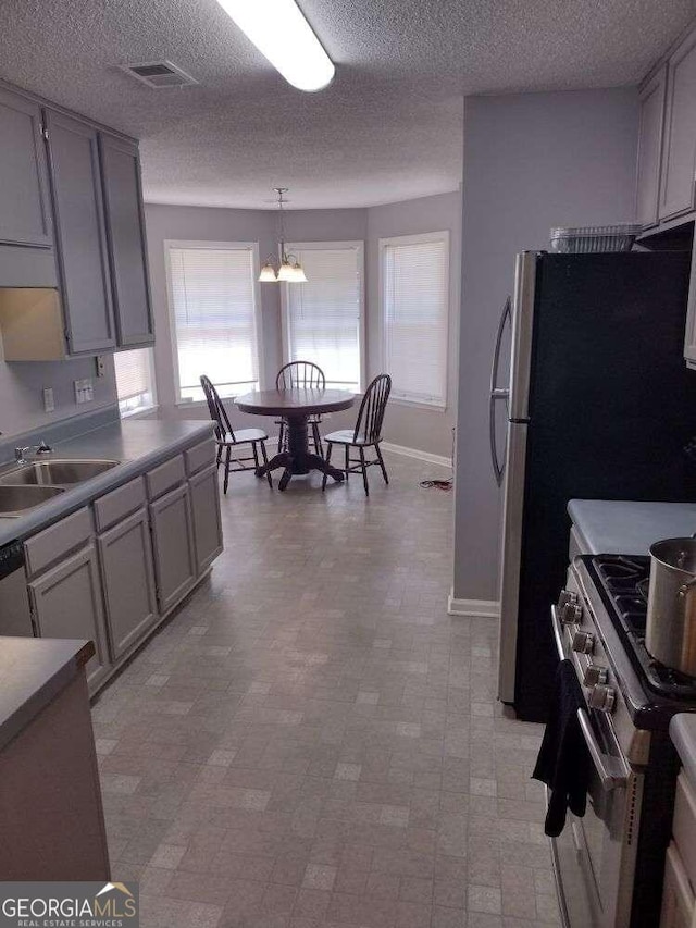 kitchen featuring decorative light fixtures, sink, stainless steel appliances, and a textured ceiling