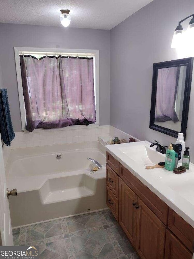 bathroom with a tub, vanity, and a textured ceiling