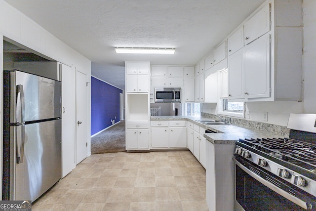 kitchen with sink, appliances with stainless steel finishes, a textured ceiling, and white cabinetry