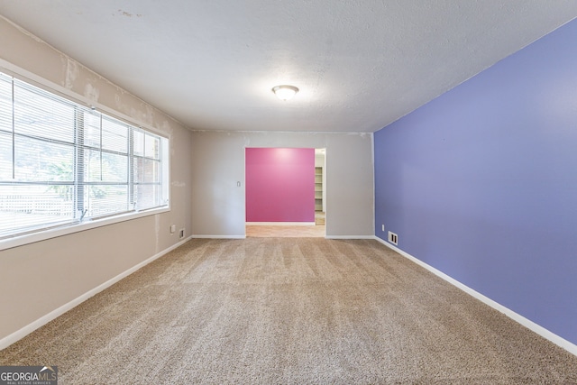 empty room featuring a textured ceiling and carpet