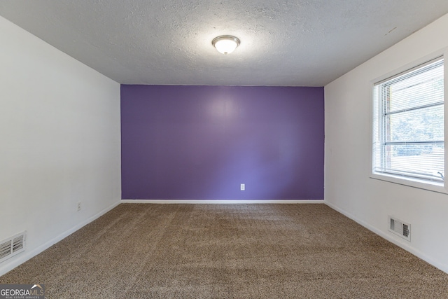 carpeted empty room featuring a textured ceiling